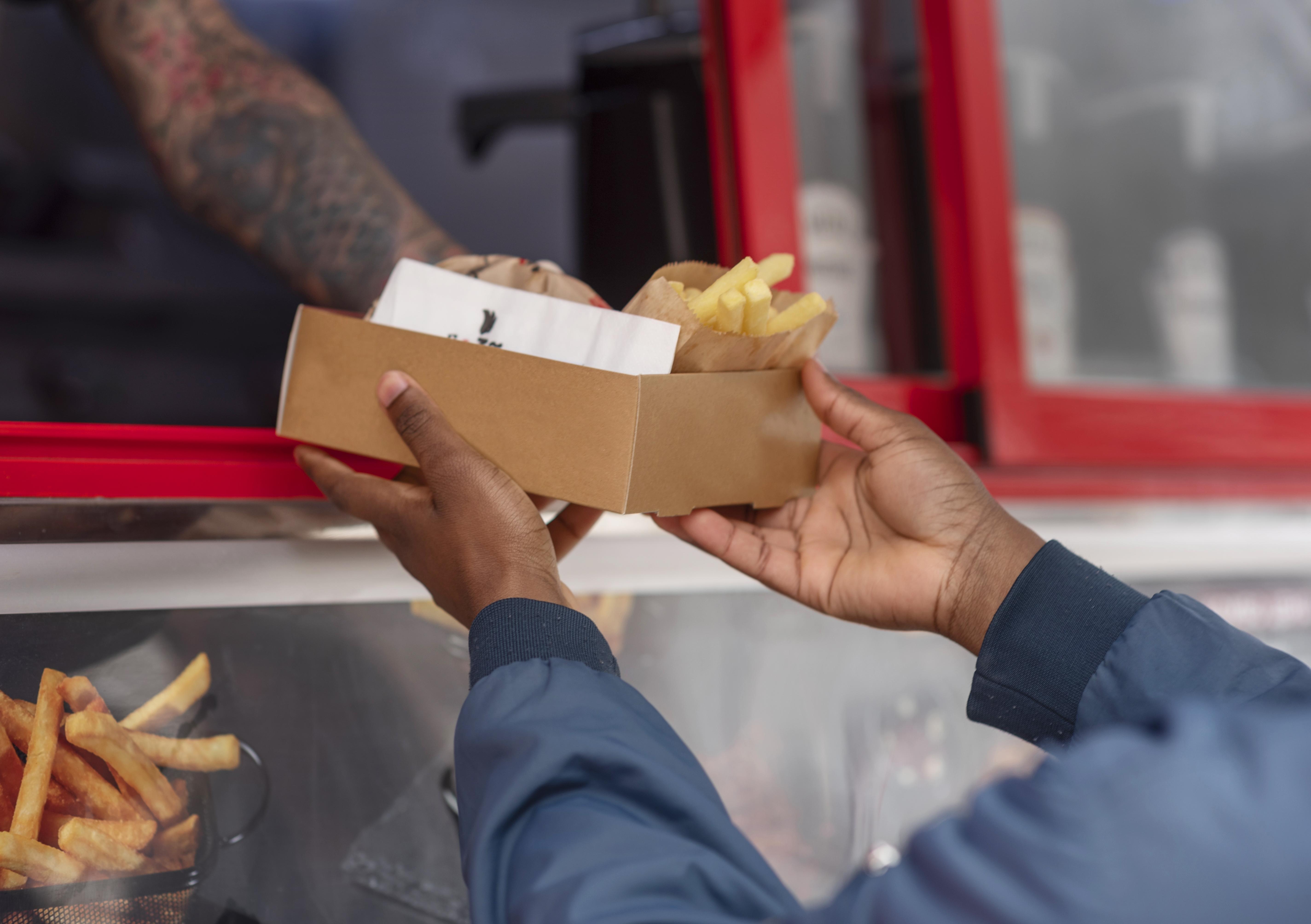 Uma pessoa entregando um lanche para outra em um food truck.